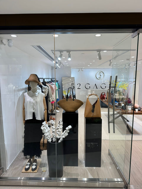Storefront display with mannequins and bags, featuring the brand '2GAG'.